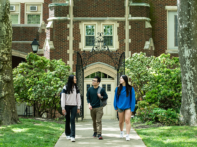 Three students walking along the Hansen Quad.