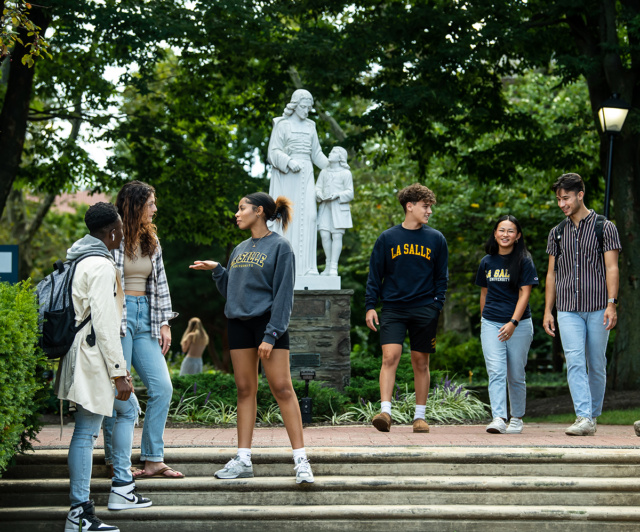 Groups of students walking and talking together with St. Joh Baptist de ɫƵ statue in the background.